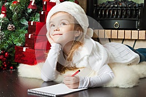 Pretty girl in Santa hat writes letter to Santa photo