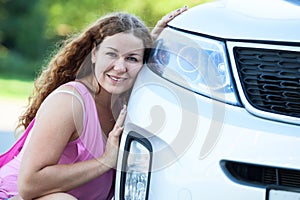 Pretty girl sitting her cheek against to the bumper of car