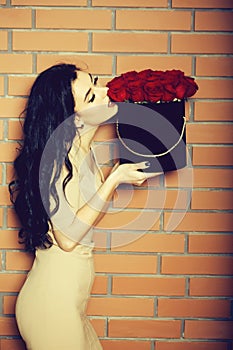 Pretty girl smelling red roses in box