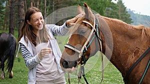 Pretty girl smiles stroking smooth the horse`s mane on the field