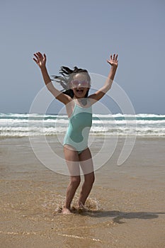 Pretty girl smiling while playing jumping on the shore of the beach