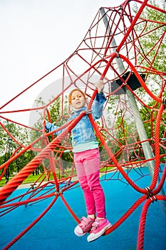 Pretty girl standing on red net of playground