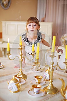 Pretty girl stands near white table with dishes