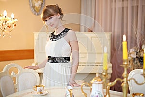 Pretty girl stands next to classic white table