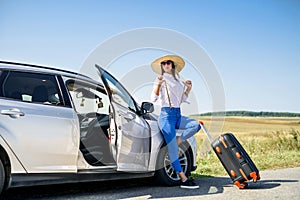 Pretty girl with suitcase standing near car and wiat for her dreaming trip photo