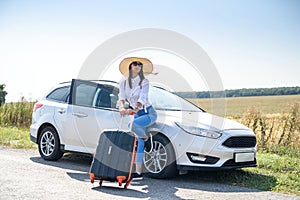 Pretty girl with suitcase standing near car and wiat for her dreaming trip photo