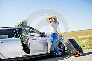 Pretty girl with suitcase standing near car and wiat for her dreaming trip photo