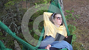 Pretty girl in sunglasses lies in a hammock in the forest