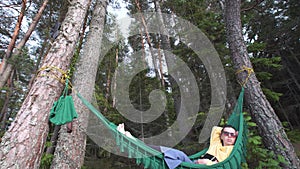 Pretty girl in sunglasses relaxing in a hammock in the forest