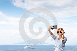 Pretty girl in sunglasses Takes a selfie photo. Sea and horizon in the background. Vacation and travel concept. Communication on a