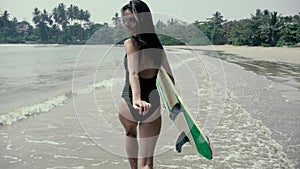 Pretty girl surfer or beautiful woman, slim brunette, in swimsuit with sexi buttocks holding yellow surfboard on