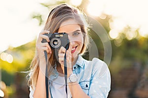 Pretty girl taking photos with a vintage camera on a sunny day