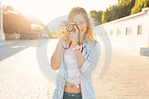 Pretty girl taking photos with a vintage camera on a sunny day