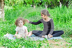 Pretty girl teaching yoga to her sister, little girls doing yoga exercises in the garden