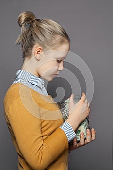 Pretty girl teen and money in glass jar on gray background