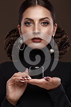 Pretty girl, unusual hairstyle, bright makeup, red lips and manicure design with a jar of nail polish in her hands