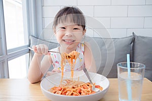 Pretty girl using fork eating spaghetti by herself