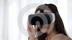 Pretty girl using futuristic VR technology and laughing, pleased with imagery