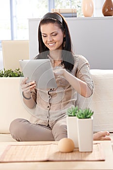 Pretty girl using tablet at home smiling