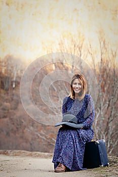 Pretty girl with vintage case on a dirtroad