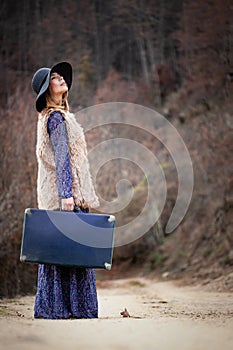 Pretty girl with vintage case on a dirtroad