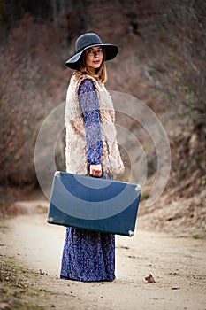 Pretty girl with vintage case on a dirtroad