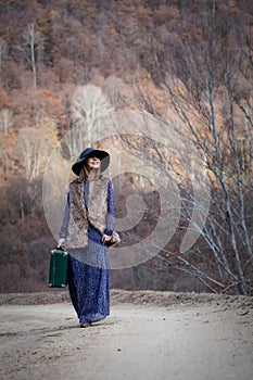 Pretty girl with vintage case on a dirtroad