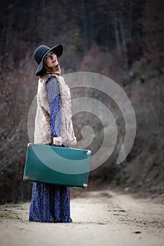 Pretty girl with vintage case on a dirtroad