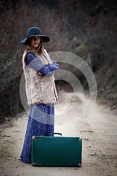 Pretty girl with vintage case on a dirtroad