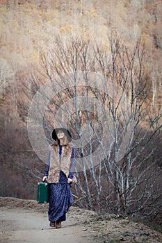 Pretty girl with vintage case on a dirtroad