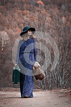 Pretty girl with vintage case on a dirtroad