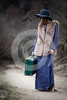 Pretty girl with vintage case on a dirtroad