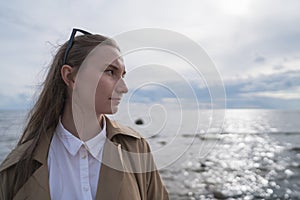 Pretty girl walking on a beach in beige trench coat