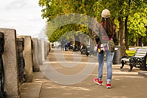 Pretty girl walking outdoors in running shoes from behind