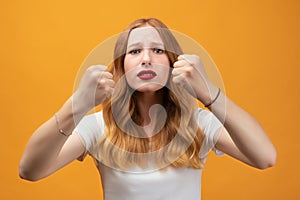 Pretty girl with wavy redhead, raising fists frustrated and furious