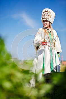 Pretty girl wearing national apparel with red bowl in hands