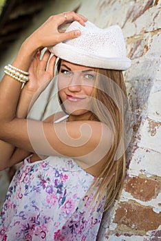 Pretty girl in white fedora hat beside old brick