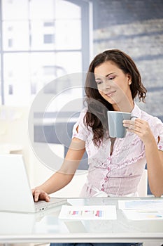 Pretty girl working on laptop in bright office