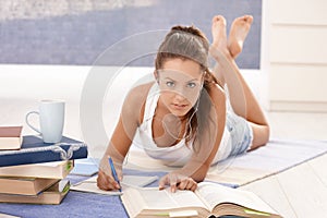 Pretty girl writing homework laying on floor