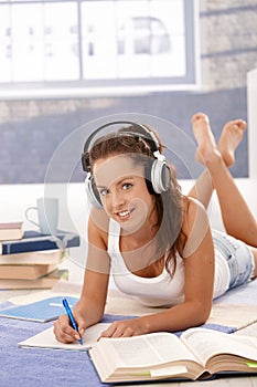 Pretty girl writing homework laying on floor