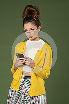 Pretty girl writing sms and looking in camera in colorful outfit