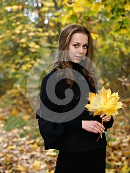 Pretty girl with yellow maple leaves on hands