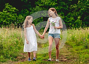 Pretty girls walking on summer meadow