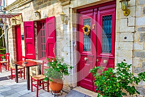 Pretty Greek tavern red front door with sidewalk tables Lefkada Greece