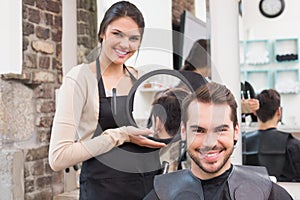 Pretty hair stylist showing man new haircut