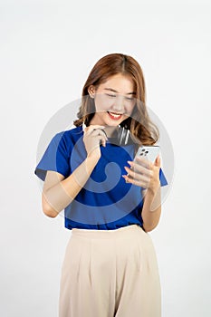 Pretty happy asian teenage girl using mobile phone playing music from smartphone application, happy smiling