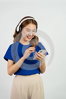 Pretty happy asian teenage girl using mobile phone playing music from smartphone application, happy smiling