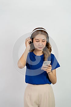 Pretty happy asian teenage girl using mobile phone playing music from smartphone application, happy smiling