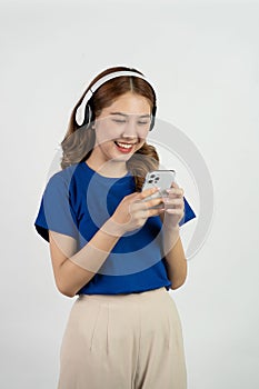 Pretty happy asian teenage girl using mobile phone playing music from smartphone application, happy smiling