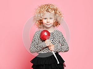 Pretty happy curly blonde hair young little child girl hold huge sweet lollypop candy surprised screaming yelling on pink